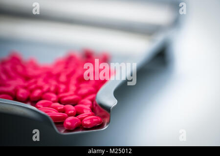 Détail d'un plan macro forme de rein rouge comprimés enrobés de sucre sur le plateau de la drogue en acier inoxydable Banque D'Images