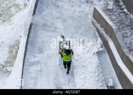 Météo russe, Moscou. Lundi, Février 5, 2018. La ville renaît après la norme mensuelle de neige il a obtenu le week-end dernier. Services municipaux de mobiliser toutes leurs ressources pour nettoyer les rues et les places de l'épais tapis blanc de flocons. La température est basse, -10C (14F), toujours de la neige légère. Non identifié, méconnaissable travailleur homme enlève la neige de la digue de la rivière de Moscou avec l'aide d'un dispositif mécanique. Crédit : Alex's Pictures/Alamy Live News Banque D'Images