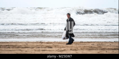 Gijon, Espagne. 05 janvier, 2018. Un homme marche sur la plage de San Lorenzo à Gijón, durant une journée de strong puits sur la mer. Au nord de l'Espagne est en alerte par la neige, les pluies, de l'escadre et de la houle. ©david Gato/Alamy Live News Banque D'Images