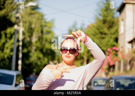 Young Girl making photo frame avec ses mains debout à street Banque D'Images