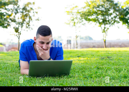 Happy student en utilisant son ordinateur portable à l'extérieur de l'université park Banque D'Images