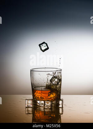 Un verre de whisky à la chute des cubes de glace Banque D'Images