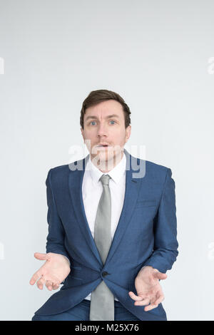 Portrait d'un homme bien habillé dans un costume à choqué et désemparé dans à l'appareil photo. Isolé sur fond blanc Banque D'Images