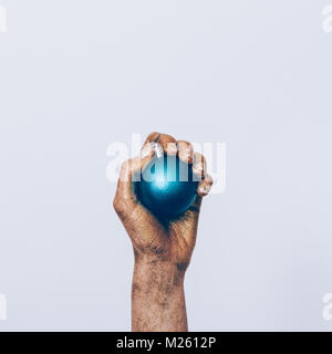 Close-up of a woman's hand holding peinture d'or dans une boule de noël bleu sur fond blanc Banque D'Images