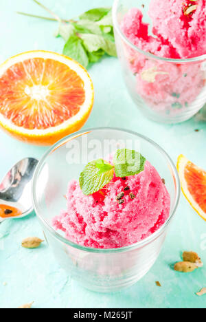 La crème glacée, sorbet orange sanguine et la cardamome, avec les oranges fraîches et menthe, fond bleu clair, copy space Banque D'Images
