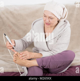 Senior woman à partir pieds pedicuring avec dispositifs spéciaux à la maison Banque D'Images