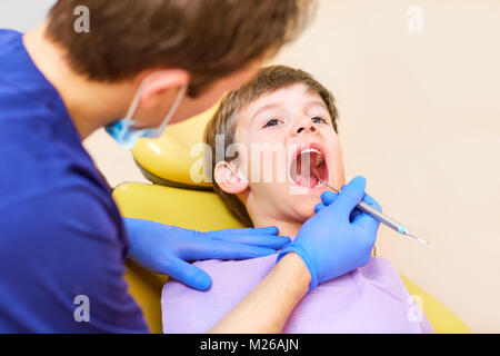 Le dentiste vérifie les dents d'un homme garçon adolescent. Banque D'Images