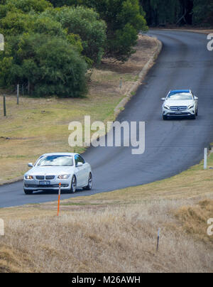 Une Mercedes blanche GLA 180 et un livre blanc des véhicules BMW roulant sur une route de campagne dans la région de Margaret River, WA, Australie. Banque D'Images