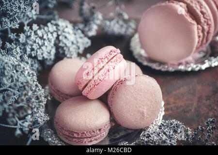 Des petits macarons sur plaque de métal avec de petites fleurs blanches sur fond de bois. Focus sélectif. Banque D'Images