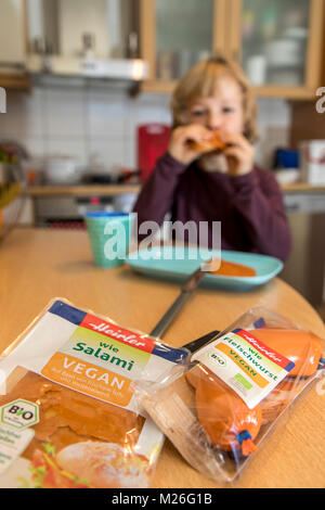 Garçon, 7 ans, végétalien, dégustation de produits de remplacement, saucisse vegan végétalien, salami, saucisses de viande Banque D'Images