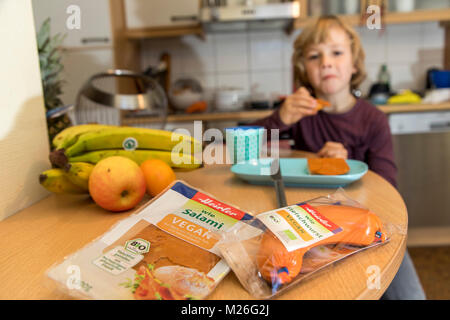 Garçon, 7 ans, végétalien, dégustation de produits de remplacement, saucisse vegan végétalien, salami, saucisses de viande Banque D'Images