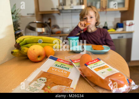 Garçon, 7 ans, végétalien, dégustation de produits de remplacement, saucisse vegan végétalien, salami, saucisses de viande Banque D'Images