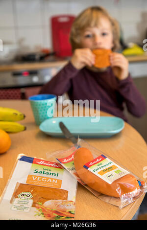 Garçon, 7 ans, végétalien, dégustation de produits de remplacement, saucisse vegan végétalien, salami, saucisses de viande Banque D'Images