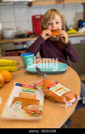 Garçon, 7 ans, végétalien, dégustation de produits de remplacement, saucisse vegan végétalien, salami, saucisses de viande Banque D'Images