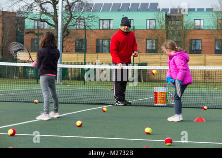 Session d'entraînement de tennis pour enfants / leçon ayant lieu sur un court de tennis avec les enfants / kids et entraîneur de tennis professionnel, en hiver. UK Banque D'Images