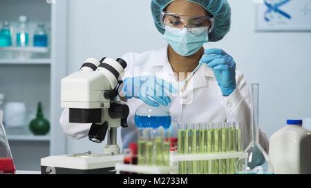 Jeune infirmier prendre échantillon liquide bleu et faire de la recherche biochimique, de laboratoire Banque D'Images