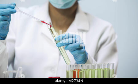 Biologiste femelle laissant tomber le sang dans le tube de liquide, travaillant au laboratoire Banque D'Images