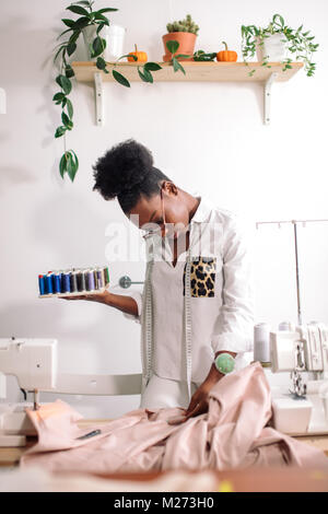 Couturière africaine holding bobines avec filetage Banque D'Images