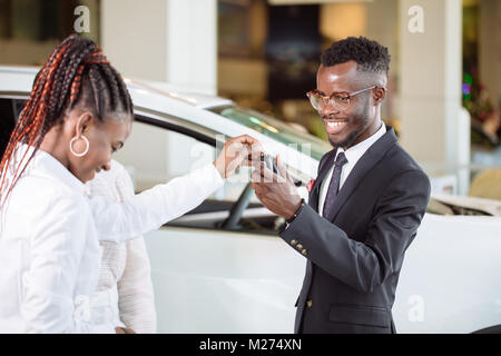 Situation des ventes en concession automobile, jeune couple obtient la clé de voiture neuve Banque D'Images