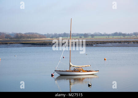 Un voile à la off côte boueuse eau calme River Deben, Martlesham, Suffolk, Angleterre, RU Banque D'Images