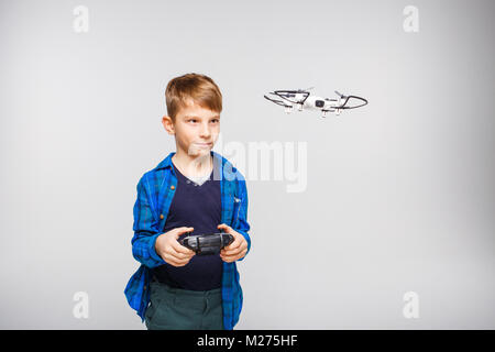 Cute boy l'exploitation dron ou quadcopter par télécommande sur fond gris. Banque D'Images