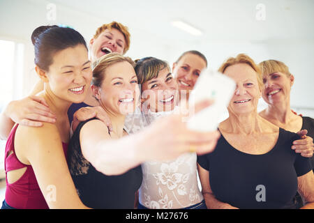 Smiling group of mature women standing arm in arm ensemble en prenant un professeur de danse avec leurs selfies pendant le cours de danse Banque D'Images