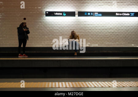 Les jeunes femmes l'utilisation de téléphones cellulaires dans la station de métro. Baixa Chiado, Lisbonne, Portugal Banque D'Images