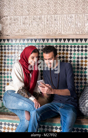 Couple arabe looking at mobile phone and smiling Banque D'Images