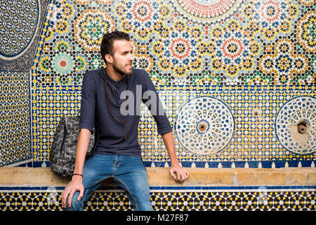 Jeune musulman homme assis en face d'art traditionnel marocain décoration ornement Banque D'Images