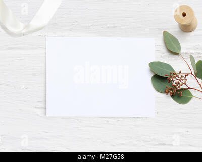 Mariage féminin maquette de bureau avec carte de papier vierge et de l'Eucalyptus populus Direction générale sur fond blanc table minable. L'espace vide. Stock photo style, bandeau web. Mise à plat, vue du dessus. Banque D'Images