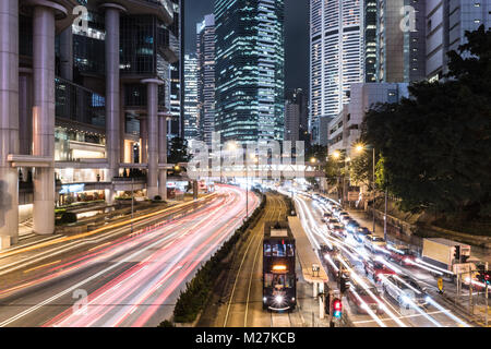 Arrêt de tramway voiture tandis que le trafic se précipiter autour d'elle au coeur de Hong Kong Central Business District de nuit dans l'île de Hong Kong SAR, Chine Banque D'Images