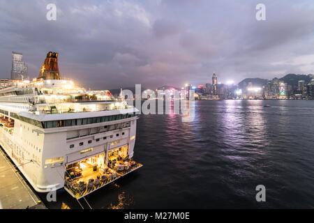 Hong Kong - Le 25 janvier 2018 : un grand bateau de croisière ancrés à l'Ocean Terminal de croisière à Kowloon avec l'île de Hong Kong skyline célèbre dans le dos Banque D'Images