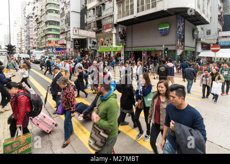 Hong Kong - Le 25 janvier 2018 : Les personnes qui traversent une rue animée de la très fréquentée du quartier commerçant de Mong Kok à Kowloon, Hong Kong Banque D'Images