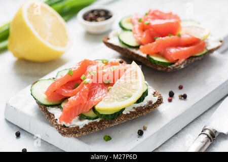 Le pain de seigle avec du saumon fumé, fromage à la crème et le concombre blanc sur une planche à découper. Hors-d'œuvre en bonne santé Banque D'Images