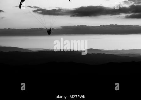 Beau coup d'une silhouette parapente voler au-dessus de Monte Cucco (Ombrie, Italie), avec le coucher du soleil sur l'arrière-plan Banque D'Images