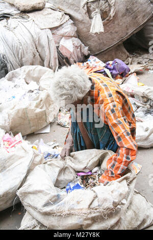 Un vieil homme passe par les ordures dans les rues d'un bidonville de New Delhi, Inde, Asie Banque D'Images