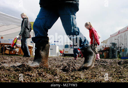 Un festival guest dans des bottes en caoutchouc est l'on marche sur le sol boueux à un festival de musique. Danemark 2006. Banque D'Images