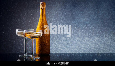 Photo de bouteille de vin en or à deux verres à vin sur fond gris Banque D'Images