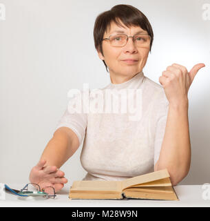 Femme de la nouvelles lunettes montre un signe qu'elle se porte bien et pousse vieux verres et d'une loupe Banque D'Images