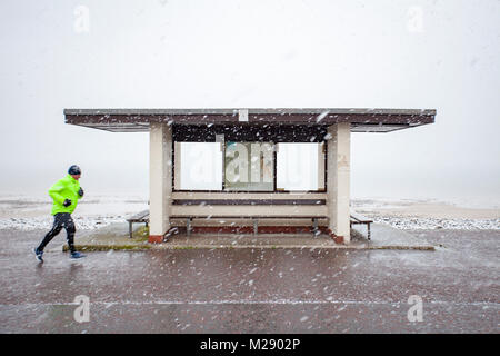 Llandudno, au Pays de Galles, le 6 février 2018. Météo britannique. Comme prévu un avertissement jaune pour la neige pour le Nord du Pays de Galles aujourd'hui avec certaines parties recevant jusqu'à 8 cm sur un terrain plus élevé. La neige très inhabituelle pour la station balnéaire de Llandudno dans le Nord du Pays de Galles comme jogger découvert sur la promenade © DGDImages/Alamy Live News Banque D'Images