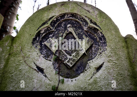 Une pierre tombale maçonnique à Tower Hamlets Cemetery avec la signature du franc-maçon square et gravée à l'emblème de la boussole en décomposition lentement en pierre. Banque D'Images