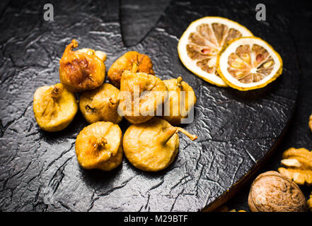 Les figues séchées et les tranches de citron sur une plaque sombre vue de dessus Banque D'Images