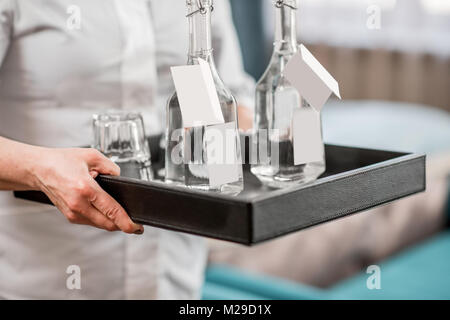 Femme tenant un plateau avec de l'eau dans la chambre d'hôtel Banque D'Images