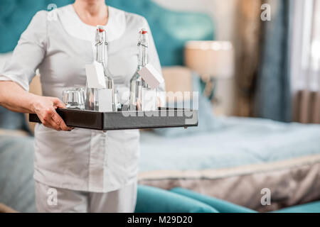 Femme tenant un plateau avec de l'eau dans la chambre d'hôtel Banque D'Images