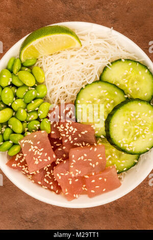 Hawaiian Poke poisson Thon bol avec les nouilles et Edamame Beans sur fond rouge Banque D'Images