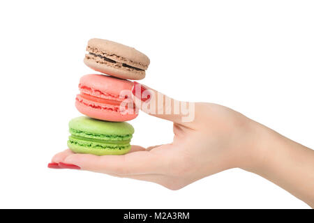 Femme main tenant trois macarons colorés. Isolé sur blanc, chemin de détourage inclus Banque D'Images