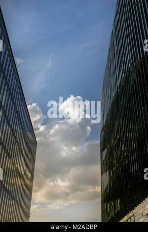 L'écartement entre deux grands bâtiments modernes, et est vu le ciel bleu avec des nuages. Banque D'Images