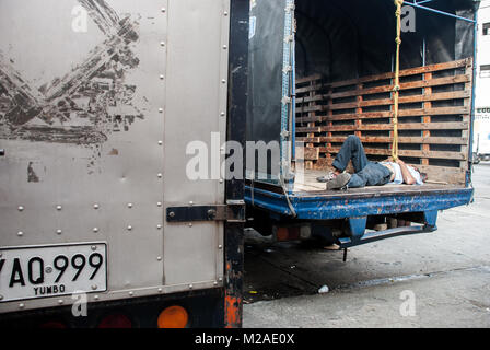Un homme dormant dans l'arrière d'un camion à l'extérieur d'un marché à Cali, Colombie Banque D'Images
