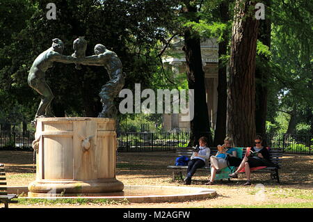 Rome, Italie - 16 mai 2012 : Fontana della famiglia dei Satiri dans le jardin Villa Borghese avec trois femmes lecture sur le banc à proximité. Banque D'Images
