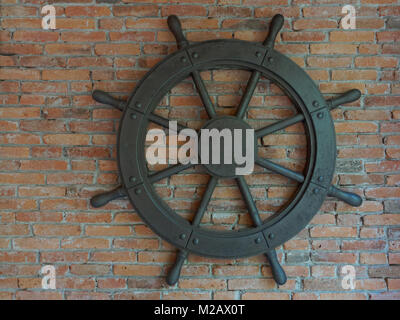 Rustique ancien vintage iron ship wheel sur fond brique Banque D'Images